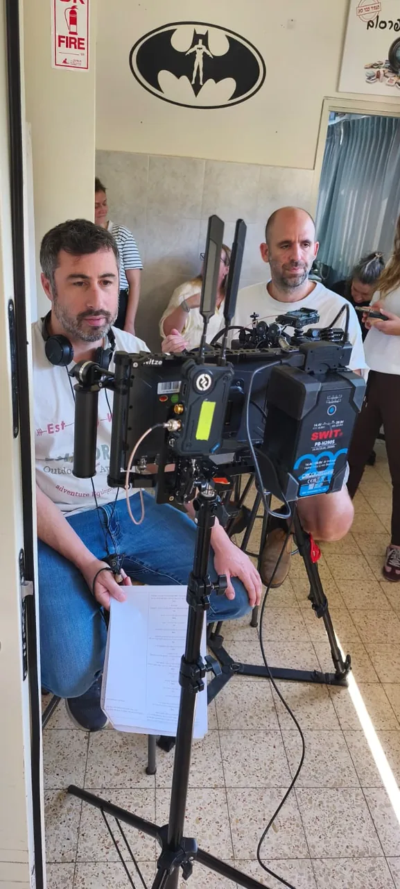 צוות ההפקה לצד מצלמה וחצובה במהלך יום צילום